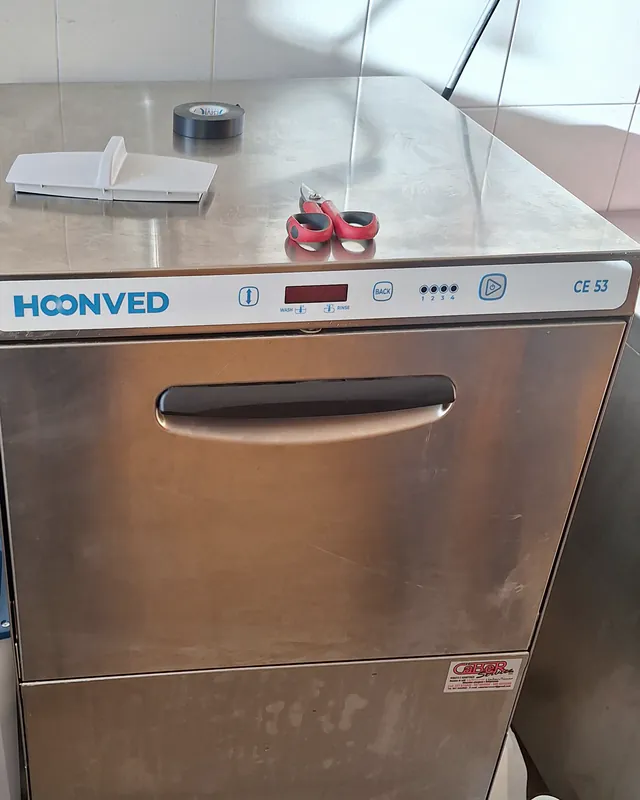 Lavastoviglie professionale Hoonved CE 53 in una cucina piastrellata, con l'adesivo di Caber Service